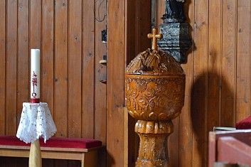 Interiér zdobí vyřezávaná křtitelnice (IČ)