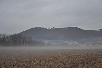 Z mlhy vystupuje vrchol se zříceninou hradu Helfštýna